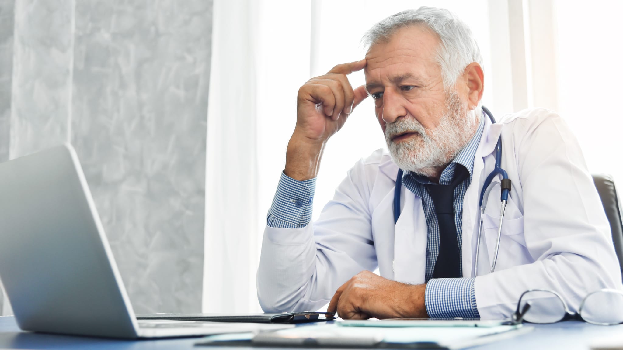 Alter Arzt denkt am PC